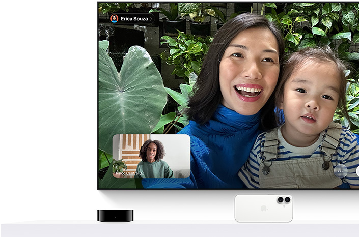 Apple TV 4K e iPhone: a tela da TV mostra uma chamada FaceTime. Uma pessoa segura uma criança. Outra pessoa está na chamada inserida