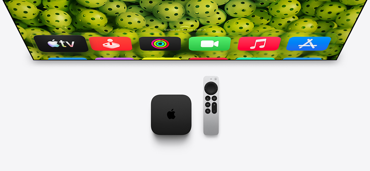 Apple TV 4K and Siri Remote below TV screen, screen shows Home Screen top row app icons over a green pickleballs background