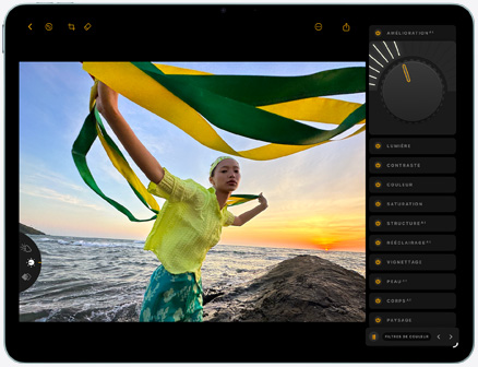 iPad Air, face avant, retouche d’une photo d’une personne tenant un tissu vert et jaune sur fond de plage au coucher du soleil, avec les outils de retouche visibles du côté droit