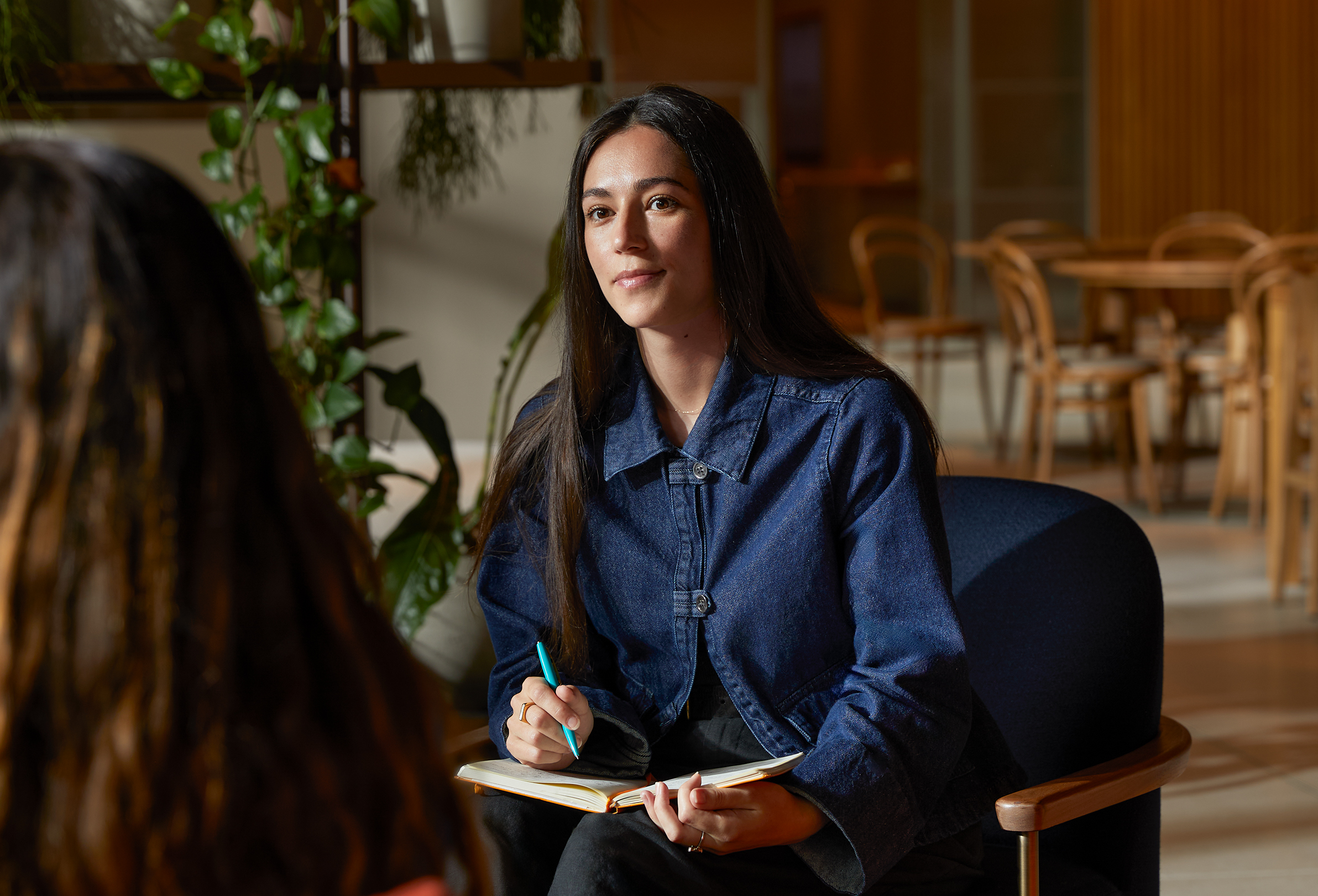 Una persona del equipo de Apple en la mesa de un área común, hablando con un colega.