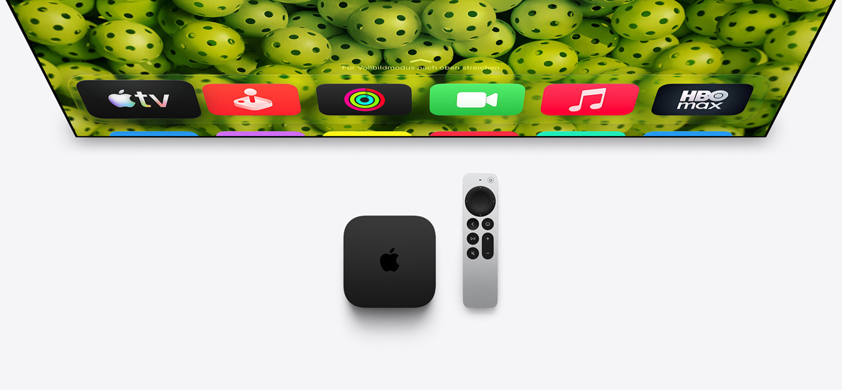 Apple TV 4K und Siri Remote unter dem Fernseher, der Bildschirm zeigt die App Symbole in der oberen Reihe auf dem Homescreen vor einem grünen Pickleball Hintergrund