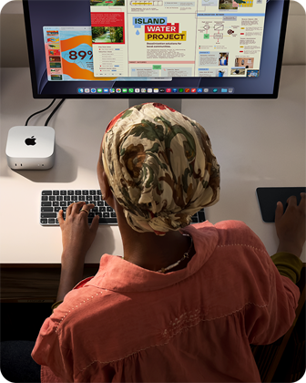 Άτομο που πληκτρολογεί σε γραφείο με Mac mini, συνδεδεμένη οθόνη Studio Display, Magic Keyboard, Magic Trackpad, διάφορα αντικείμενα
