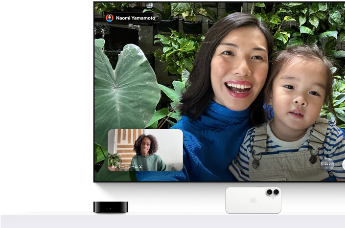 Apple TV 4KとiPhone：テレビ画面にFaceTime通話が表示されている。小さな子どもを抱えた人物と、小さな画面に通話相手の人物が映っている