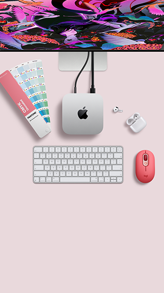 „Mac mini“ iš viršaus: sidabro spalvos aliuminio korpusas, užapvalinti kampai, centre – blizgus juodas „Apple“ logotipas, prie įrenginio prijungtas laidas; viršuje iš dalies matomas „Studio Display“, atidarytas „AirPods 4“ dėklas, „Pantone“ spalvų pavyzdžiai, skaičių klaviatūra ir pelė.