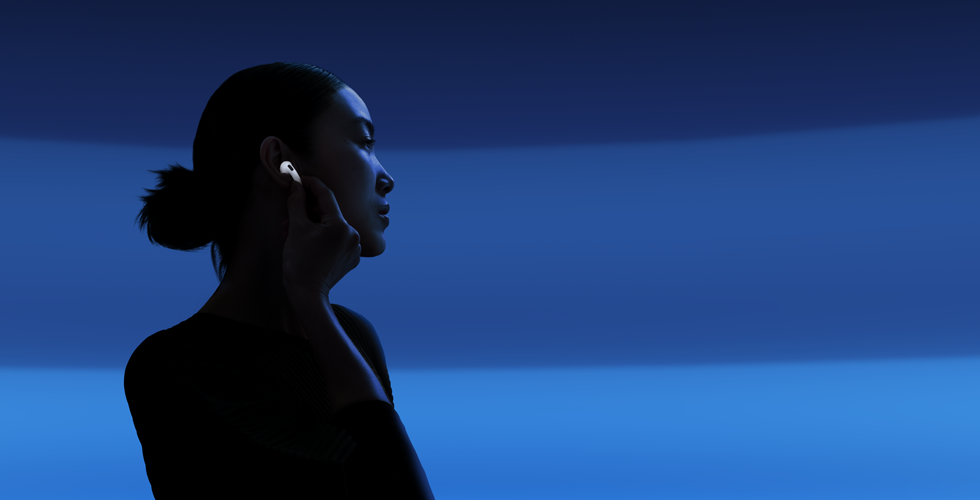 Osoba drží palcom a ukazovákom stopku svojich slúchadiel AirPods 5, aby prepla medzi jednotlivými režimami počúvania