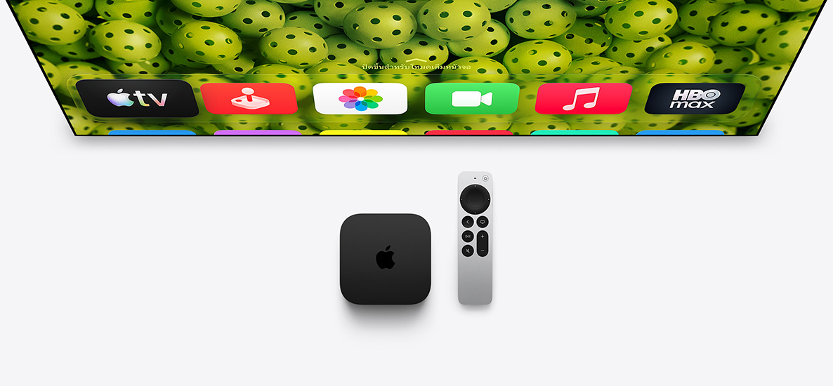 Apple TV 4K และ Siri Remote อยู่ใต้หน้าจอทีวี, หน้าจอแสดงไอคอนแอปแถวบนสุดของหน้าจอโฮม บนพื้นหลังรูปลูกพิกเคิลบอลสีเขียว
