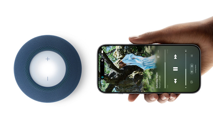 HomePod mini 2 and iPhone: A hand holds iPhone beside blue HomePod mini 2 for handoff feature