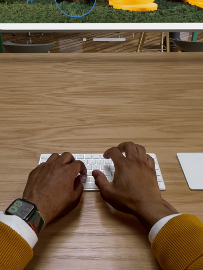 Two hands positioned over a Magic Keyboard