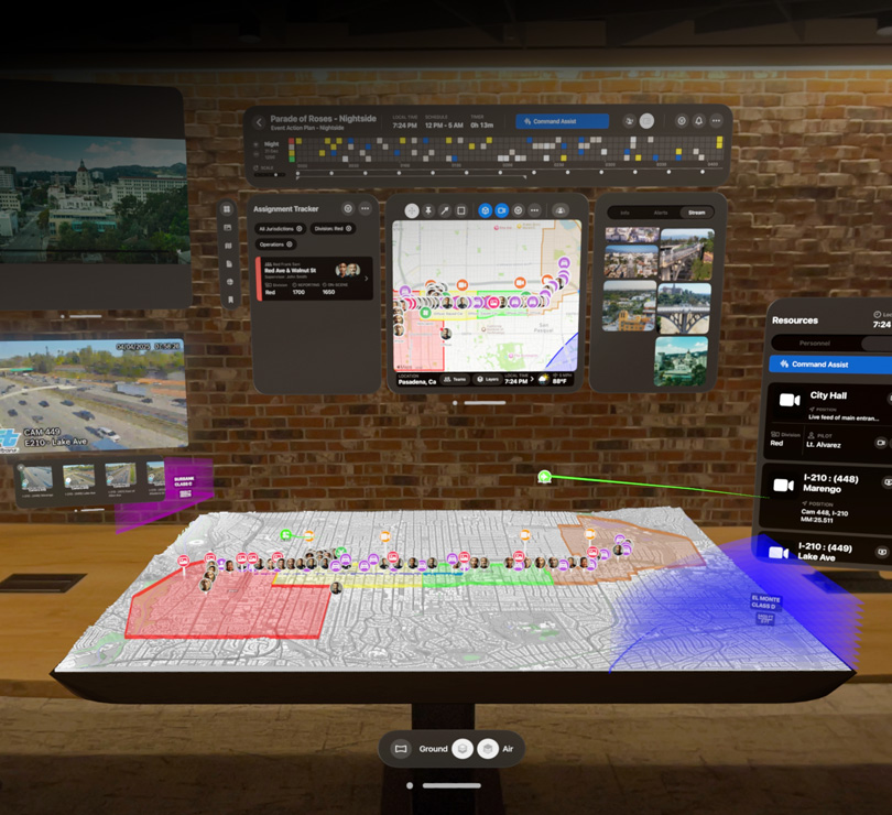 Mehrere digitale Dashboards mit Luftaufnahmen von Pasadena, einem 3D Stadtplan, Live Video Feeds und Ressourcenplänen schweben über einem Tisch