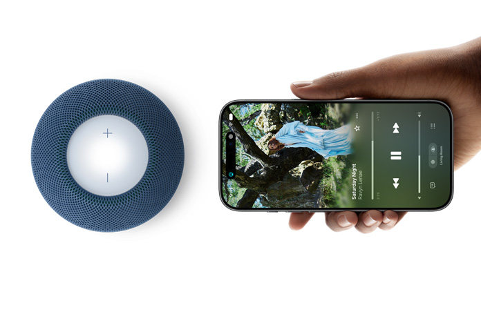 HomePod mini 2 and iPhone: A hand holds iPhone beside blue HomePod mini 2 for handoff feature