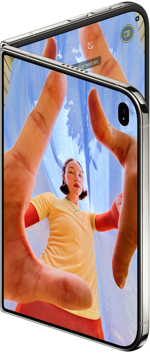 iPhone Duo, สีสตาร์ไวท์, กางเปิดเล็กน้อย, แอปกล้องบนจอภาพด้านนอกพร้อมกล้องหน้า Center Stage, จอภาพด้านในแสดงคลังแอปรูปภาพ
