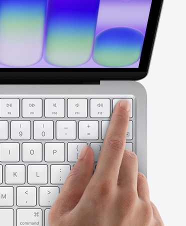 MacBook Neo, Farbe Silber, der Finger einer Person auf dem Touch ID Sensor in der oberen rechten Ecke der Tastatur
