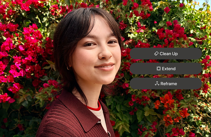 Fotografia de uma pessoa sorridente com cabelo castanho, vestida com uma camisola castanha e rodeada por flores vermelhas; demonstração de edição de fotografias com IA com as opções Limpar, Expandir e Reenquadrar apresentadas sobre a fotografia